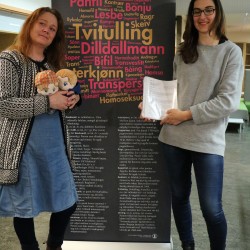 Hege Braathen and Dijana Stupar, two of those who initiated the auction bid, pose with the manuscript and to custom made doll versions of characters Isak and Even, also known under their couple name EVAK.